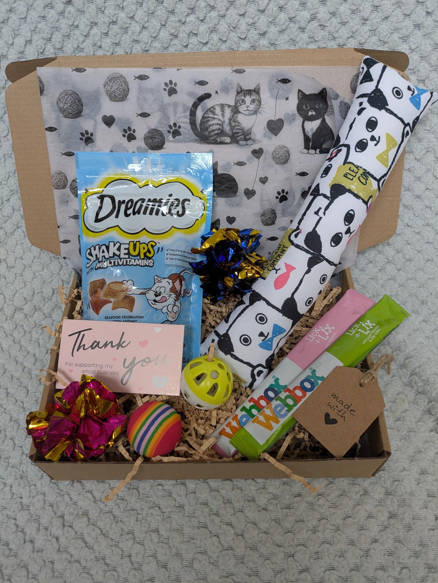 Open gift box with cat toys, premium treats, colorful balls, and personalized thank you card.