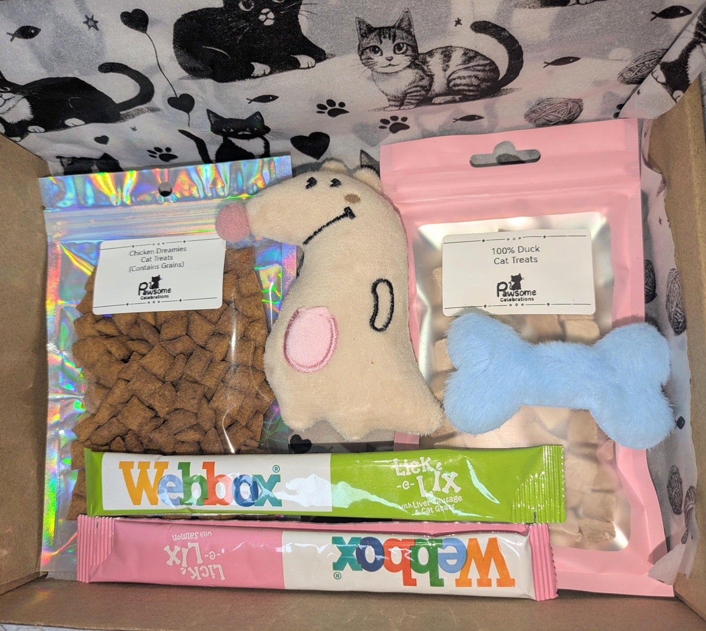 Small cat treat box with fish-shaped biscuit pack, pink and blue soft toys, and two Webbox cat treat sticks in assorted.