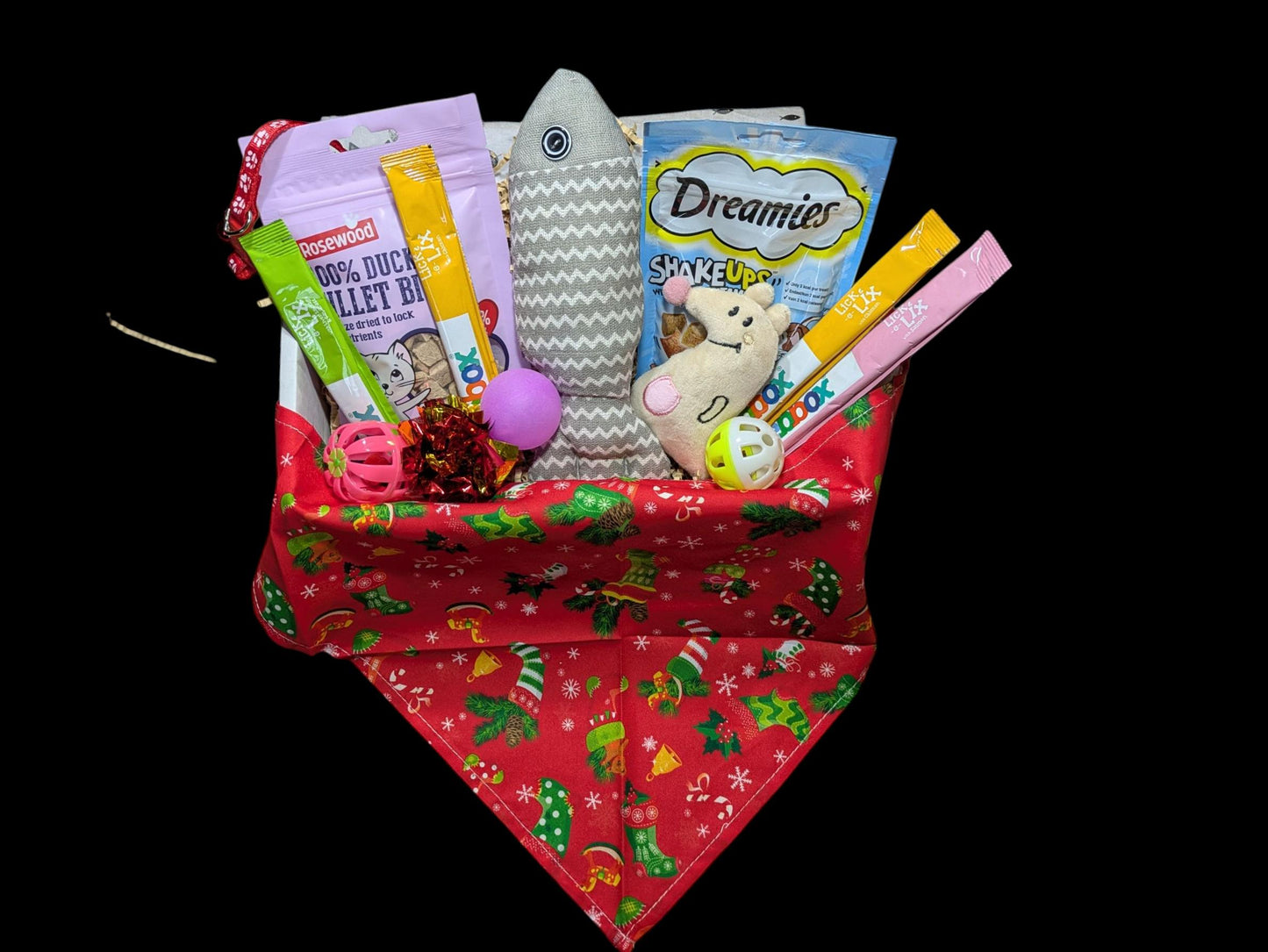 Large festive red cat hamper with Christmas patterns filled with cat treats and toys including a fish-shaped toy and.
