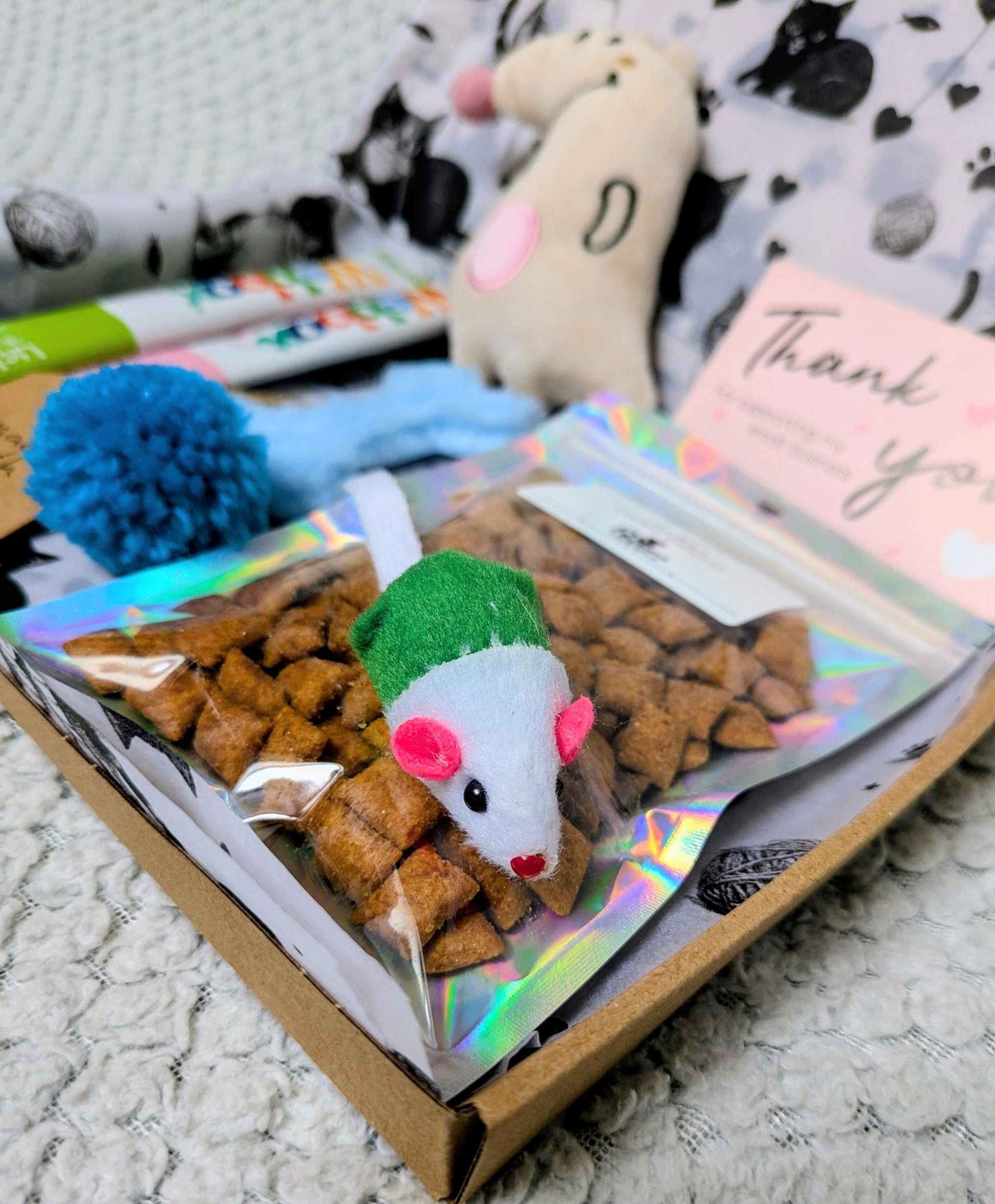Mini cat treat box with mouse toy, pom-pom ball, crunchy treats, and thank you card.