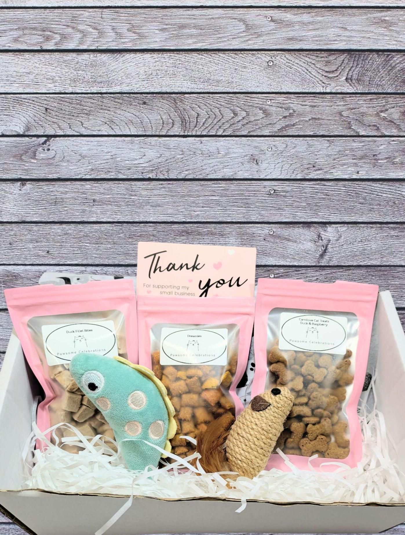 Medium pink cat treat box with three clear snack bags, plush mouse and fish toys, and a thank you card.