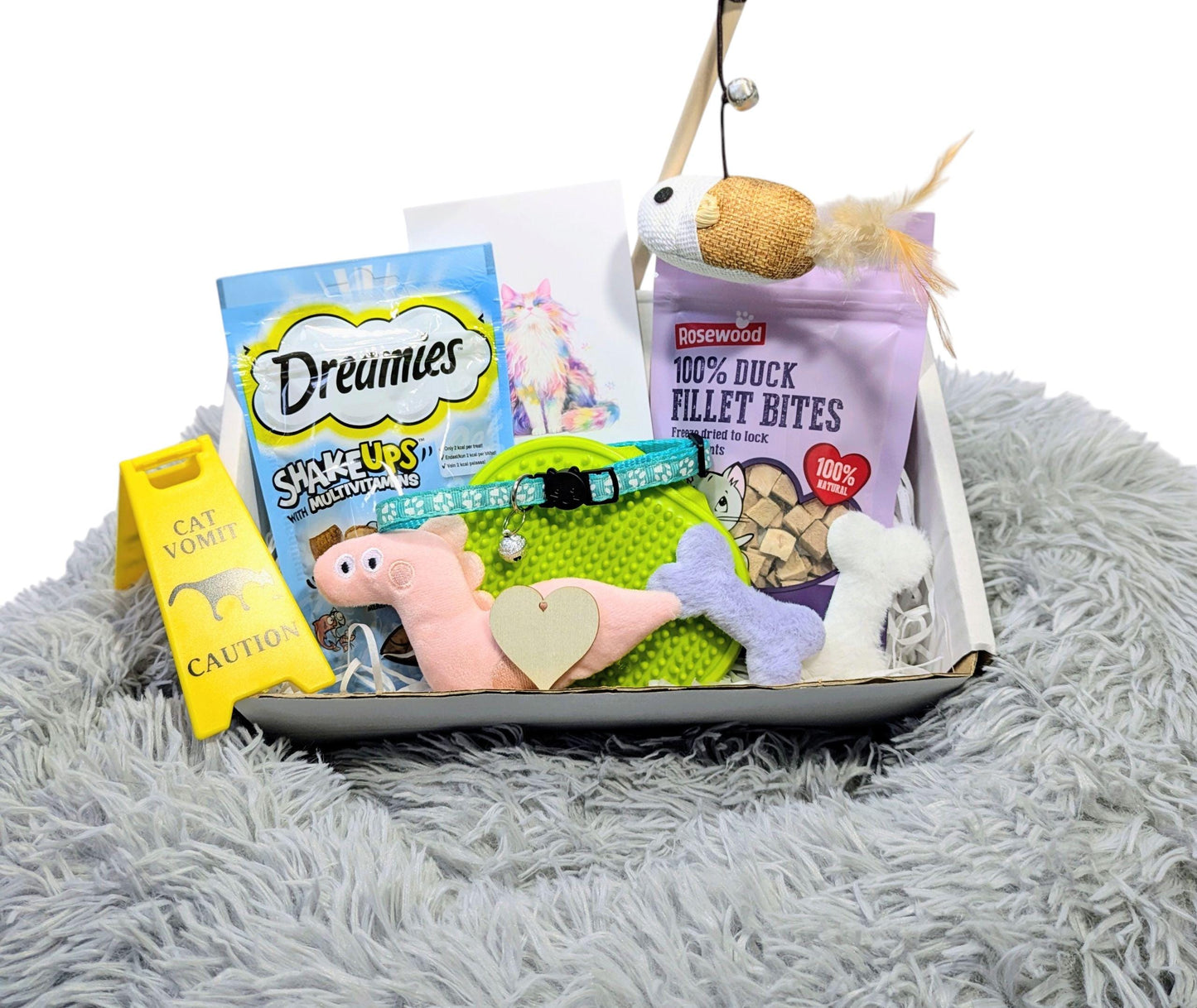 Luxury cat gift box with grey plush bed, pink toy mouse, green fish toy, treats, collar, and accessories.