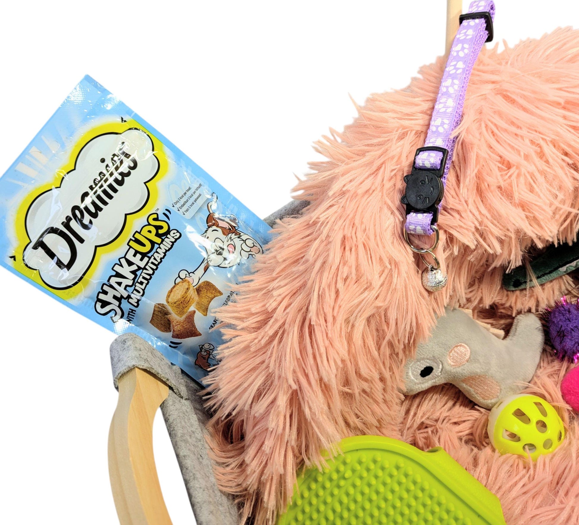 Luxury personalised cat gift box featuring a fluffy pink bed, a patterned purple collar, catnip toys, treats, and a green.