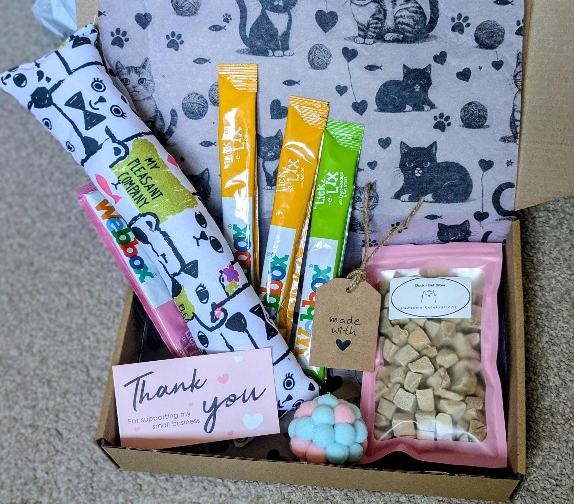 Cat treat box with catnip kicker toy, assorted cat snacks, thank you card, and cat-patterned fleece blanket.