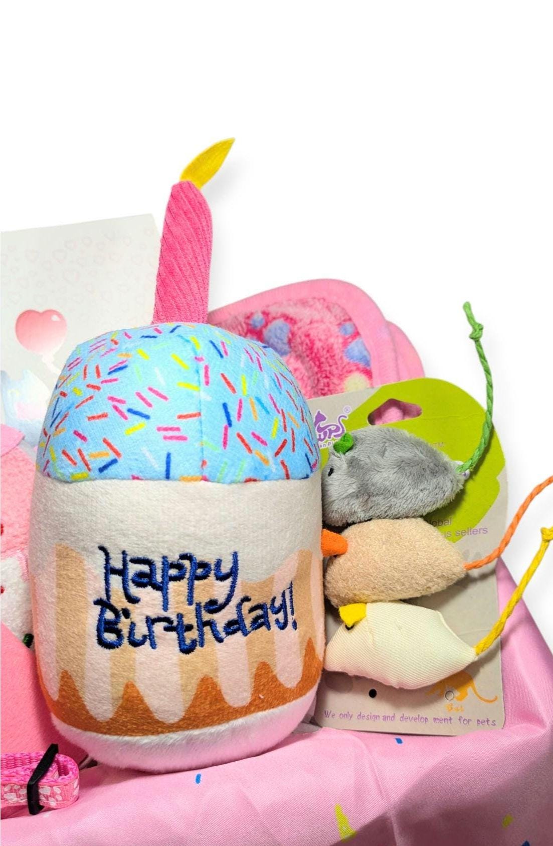 Handmade cat birthday gift box with cupcake toy, pink candle, and assorted cat toys in pastel colors.