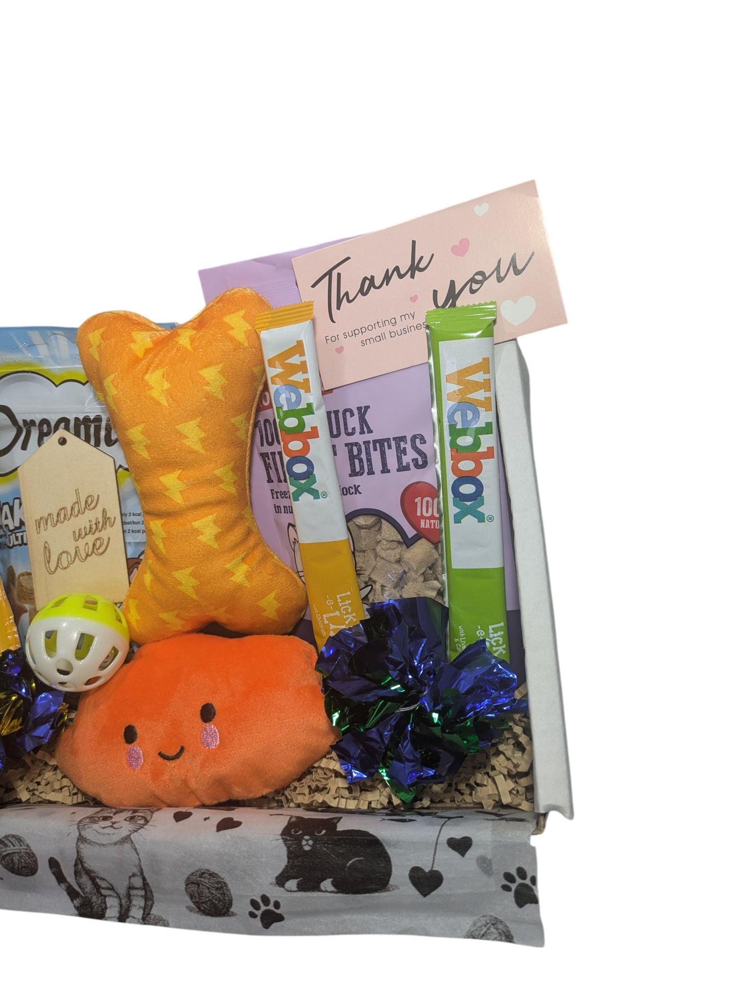 White gift box with personalized thank you card, orange bone toy, plush orange crab toy, cat treats, and shiny pom-poms.