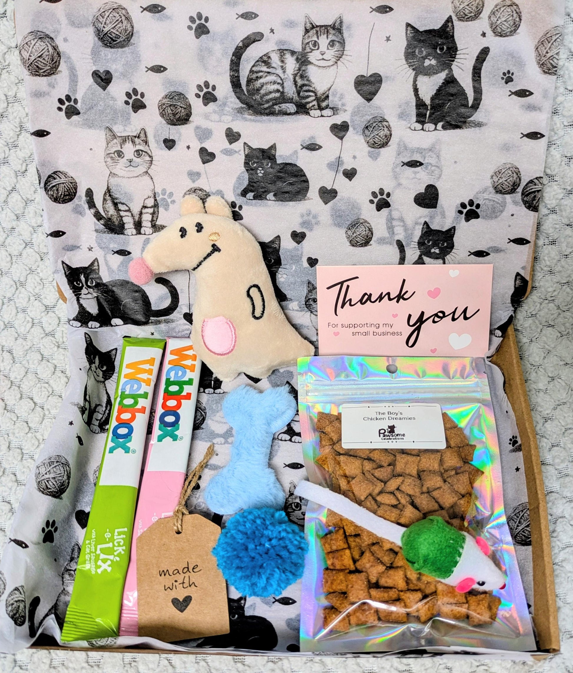 Decorative gift box with cat-themed wrapping, plush mouse toy, two Webbox cat treats, and a thank you card.