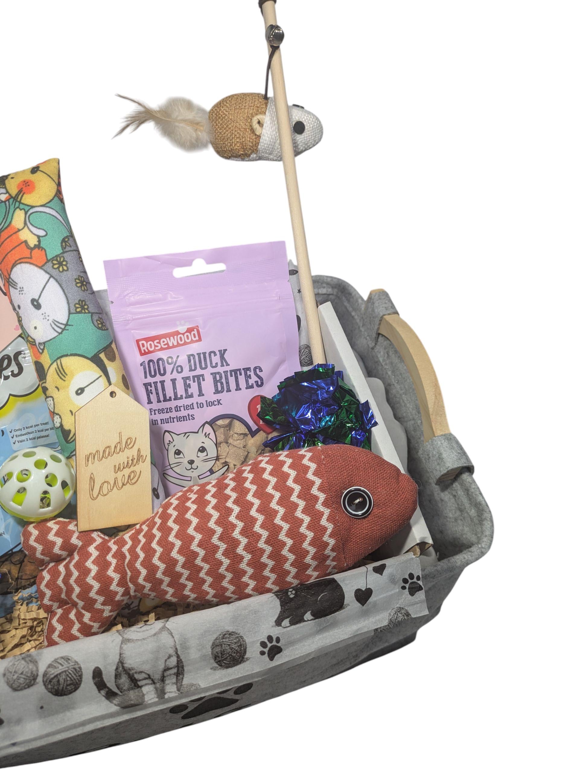 Grey cat treat hamper with fish-shaped toys, feather wand, treats, and personalized wooden tag.