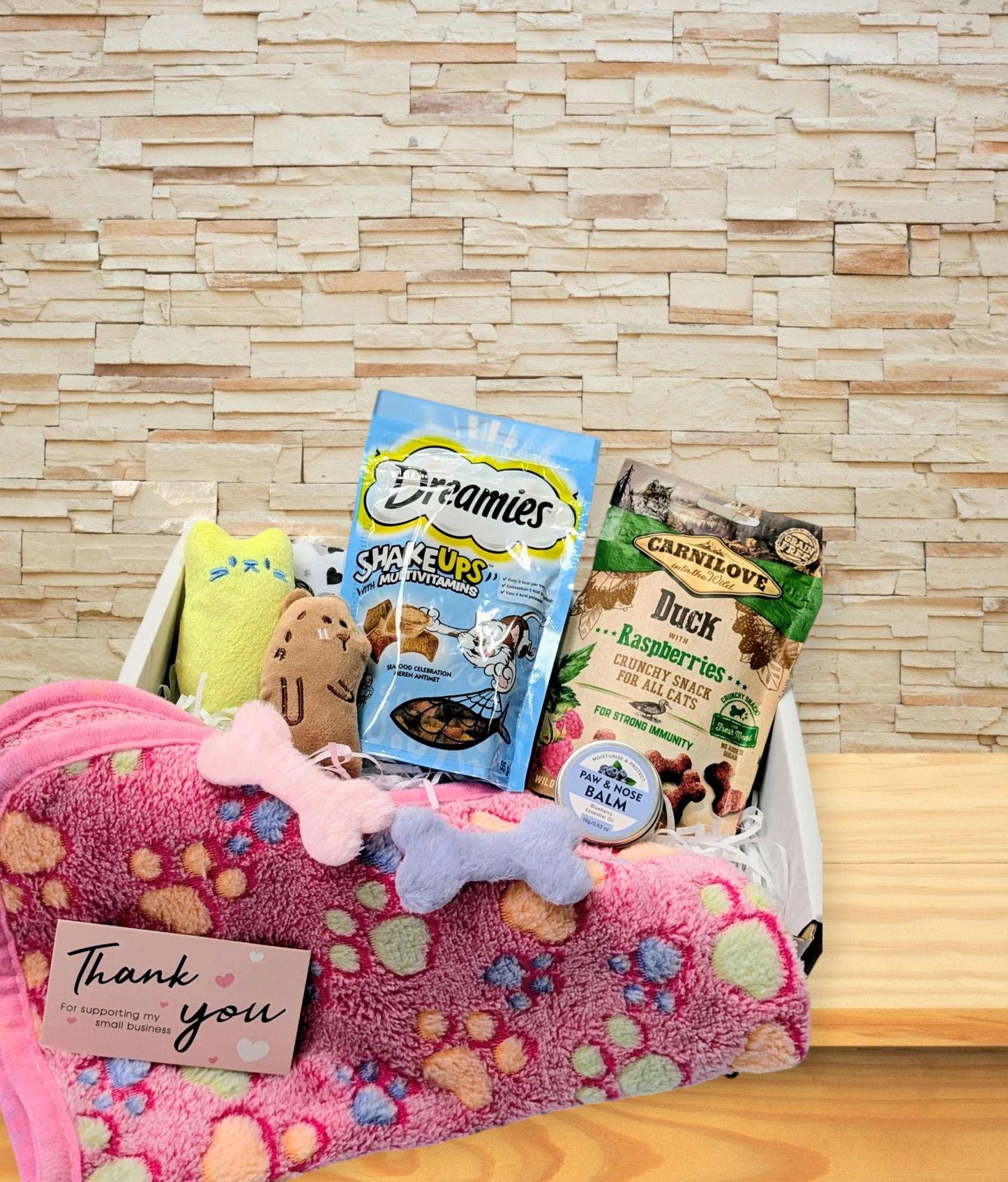 White wooden gift box with personalised cat treat hamper including pink paw-print blanket, plush toys, Dreamies treats, and.