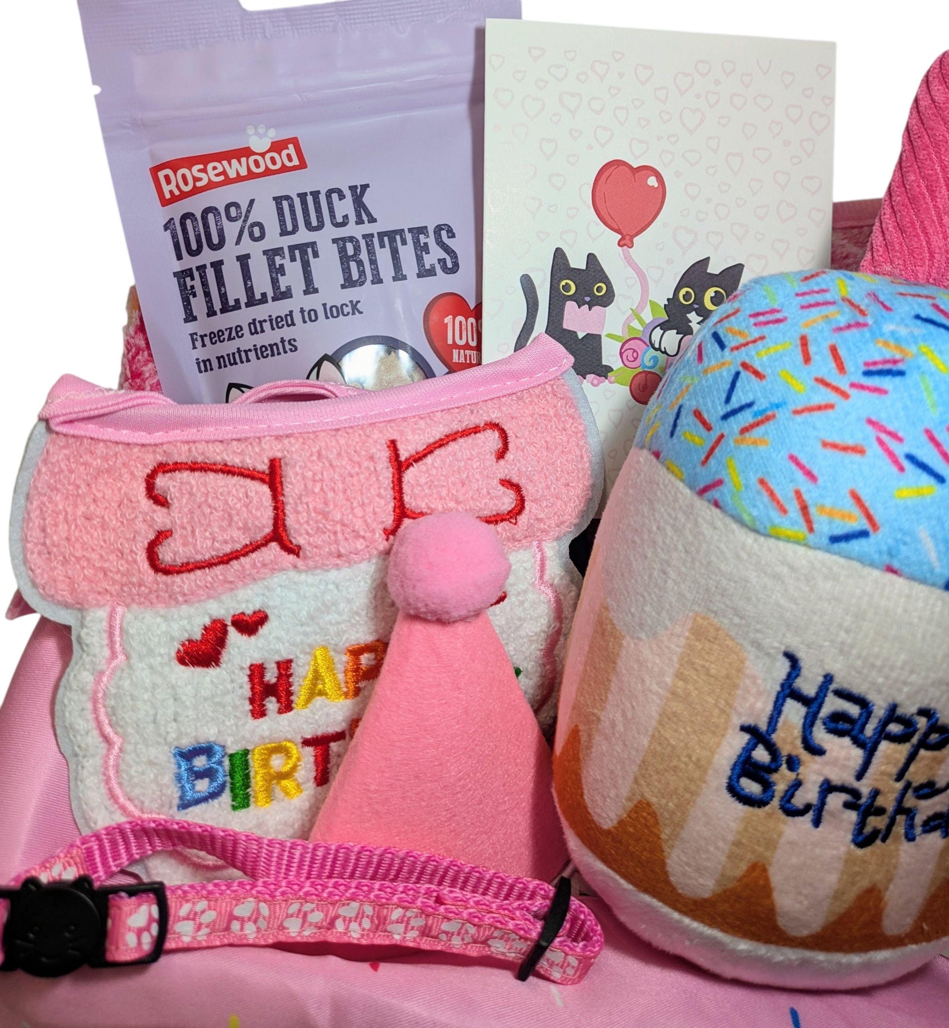 Pink birthday harness with bow and "Happy Birthday" text, pink party hat, blue sprinkle cupcake toy, duck fillet bites bag,.