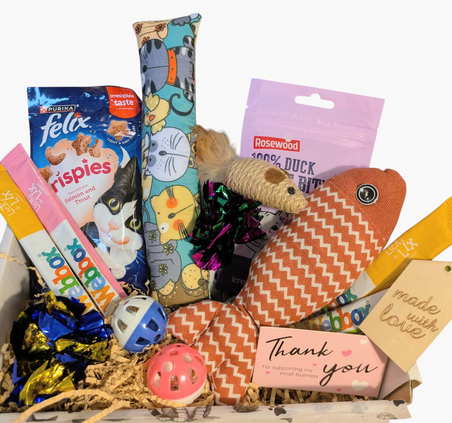 Open cat treat gift box with catnip pillow, fish-shaped toy, cat treats, and assorted colorful toys.